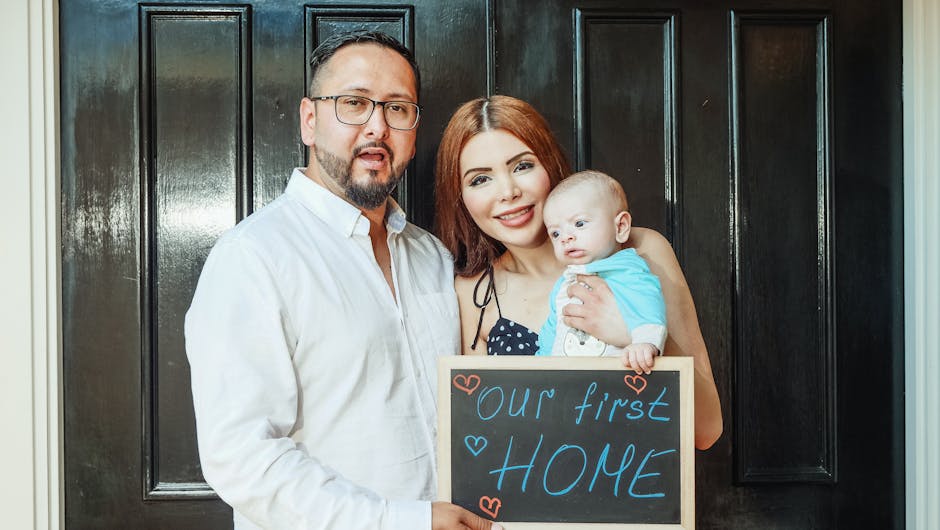 A joyful family stands at their new home's entrance holding a 'our first home' sign.